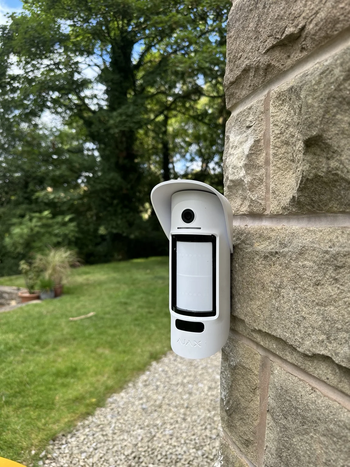 Close-up of white Ajax MotionCam Outdoor detector installed on stone