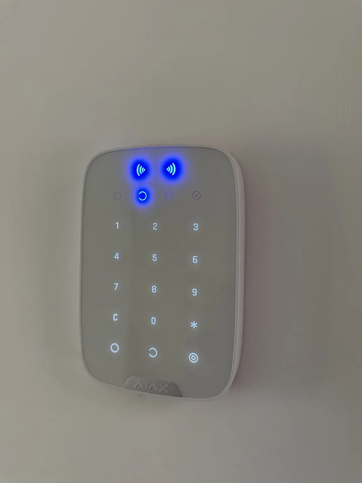 Illuminated white Ajax alarm keypad installed inside the bungalow