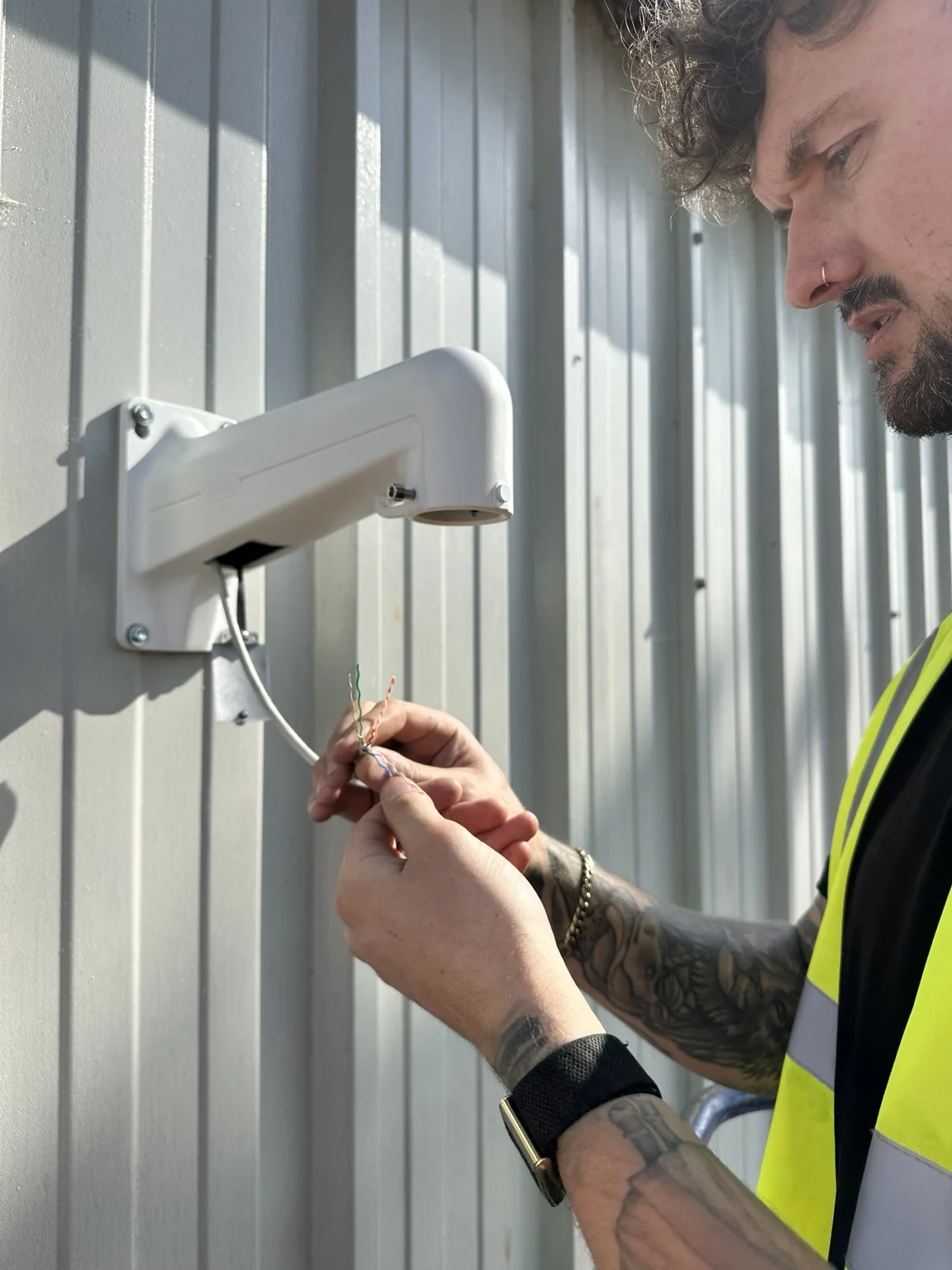 NOX installer preparing CCTV cabling on an industrial wall